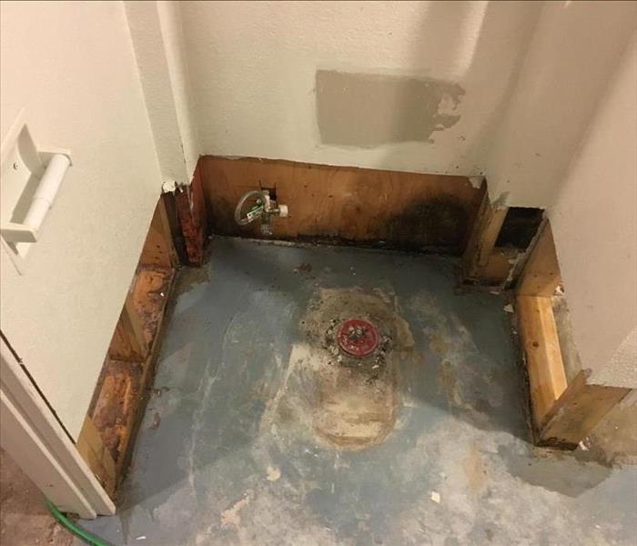 A bathroom floor missing baseboard, tile, and a toilet. 