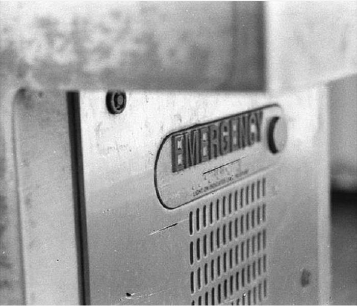 A black and white photo of an emergency call box on a college campus.