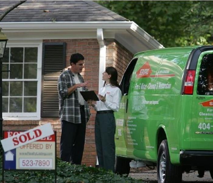 A home owner and a SERVPRO employee standing next to a “Sold” sign.