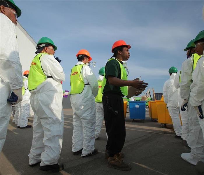 A project manager briefs Servpro technicians in full PPE on work to be done. 