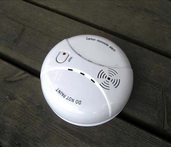 A carbon monoxide detector attached to wood plank ceiling. 